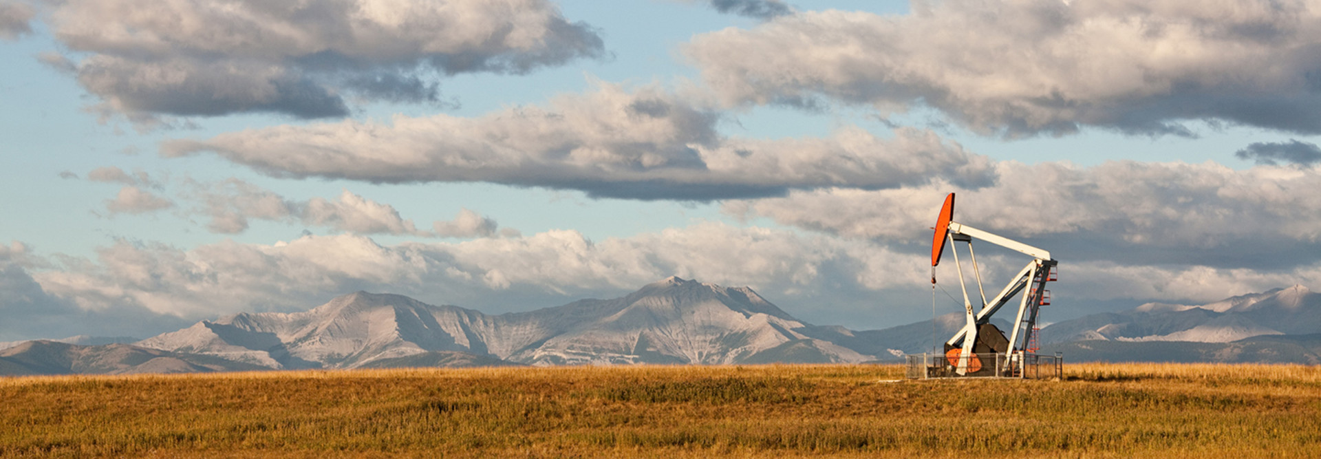 Remote oil well in Alberta, Canada, with mountains in the background 