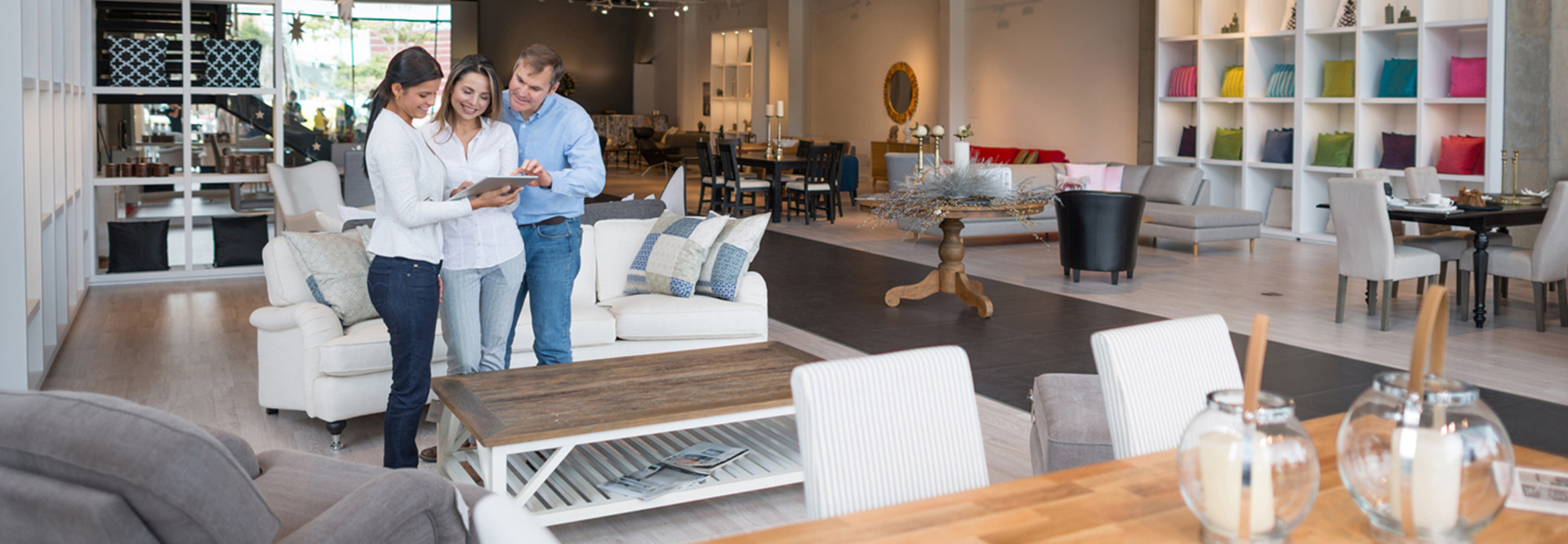 Couple shopping in a retail furniture store being helped by an associate with a tablet
