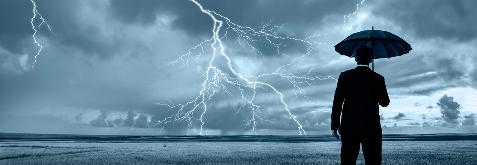 Man with umbrella and lightning on the horizon 