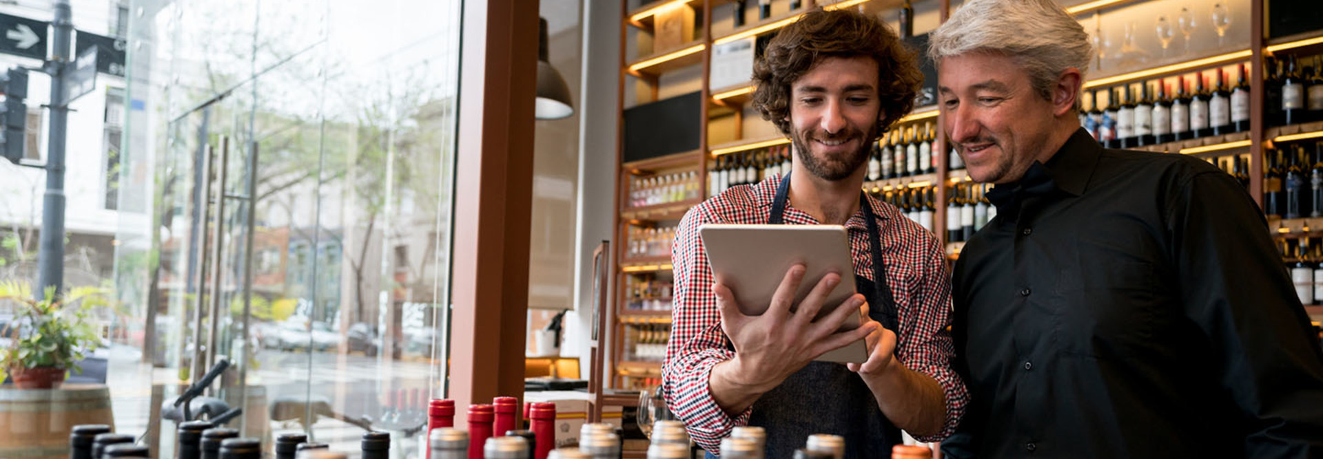 Salesman showing a wine app to a customer on a digital tablet at a winery both looking very happy and smiling