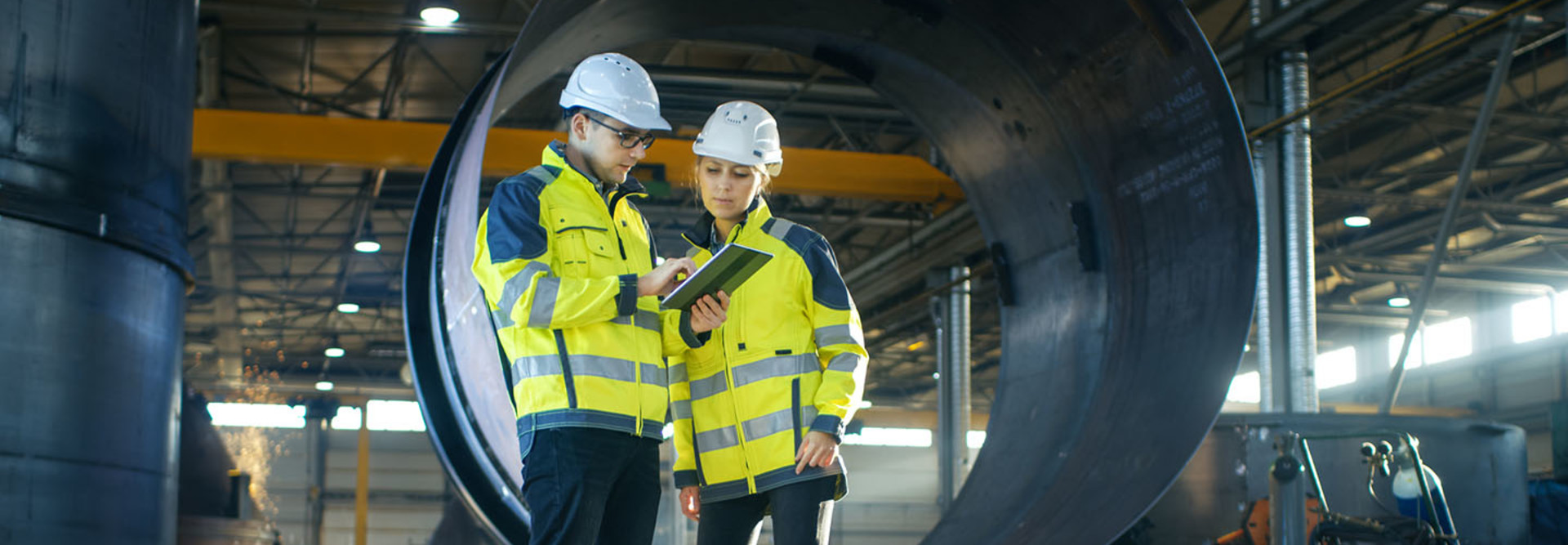 Industrial Engineers in Hard Hats Discuss New Project while Using Tablet Computer