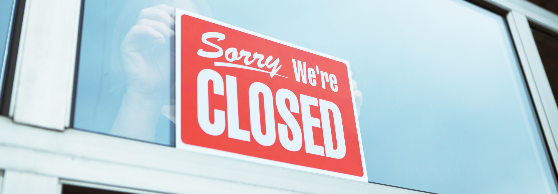 A retailer hangs a "Closed" sign in a store window