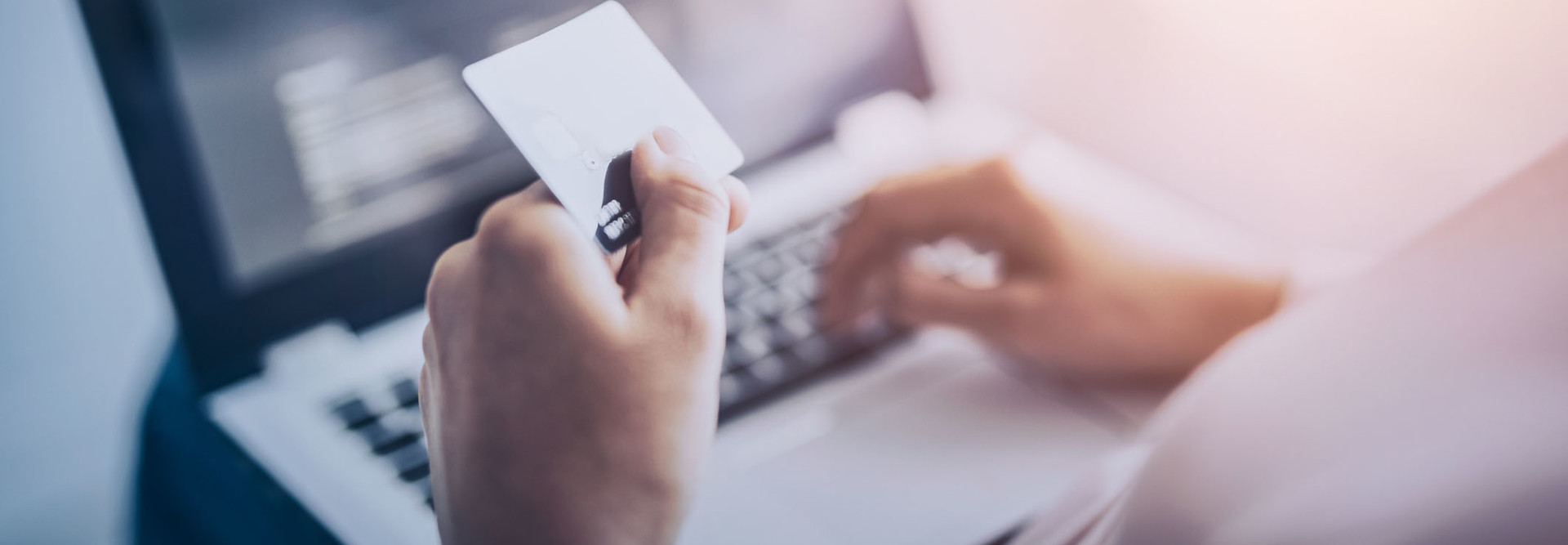 person holding credit card over computer