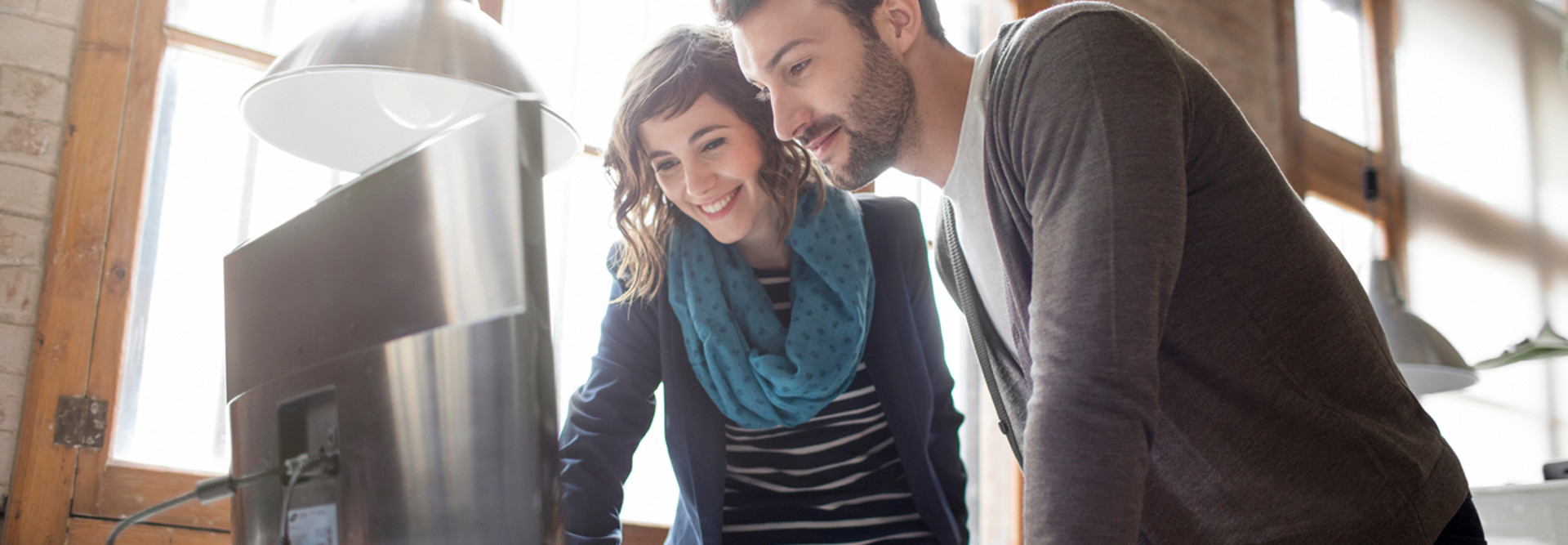 Two young people, a woman and man, working in an office and looking at a computer monitor