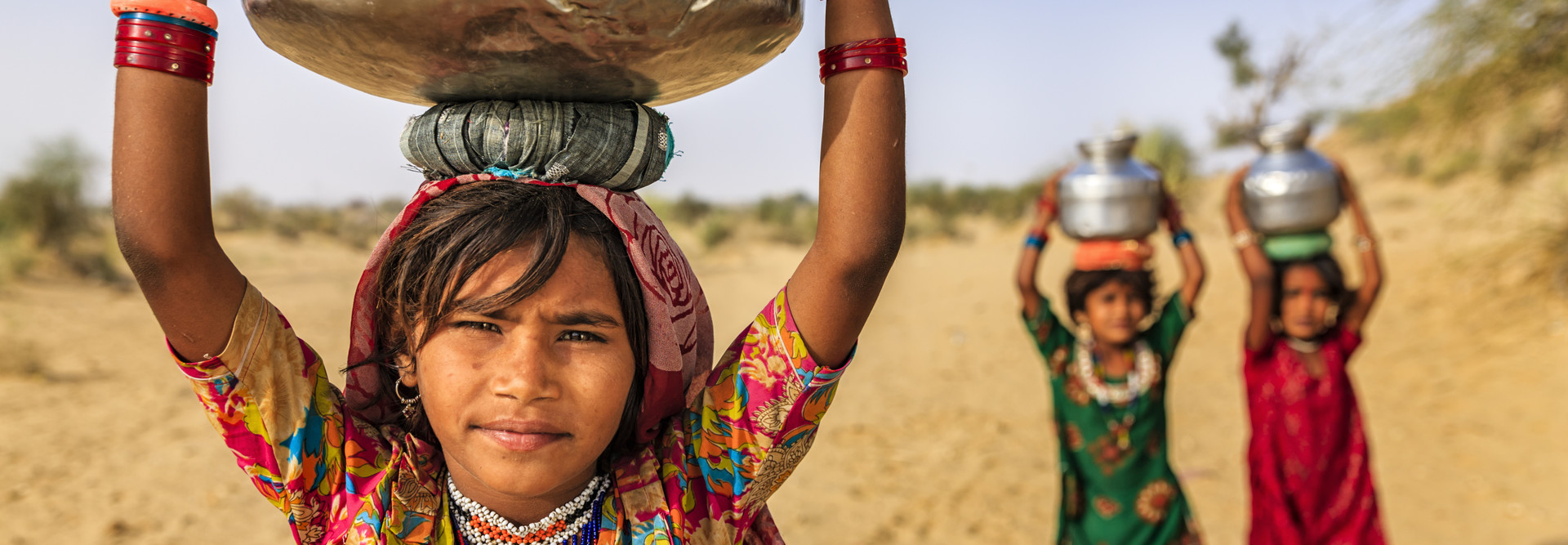 Young girls collect water from a well in India.