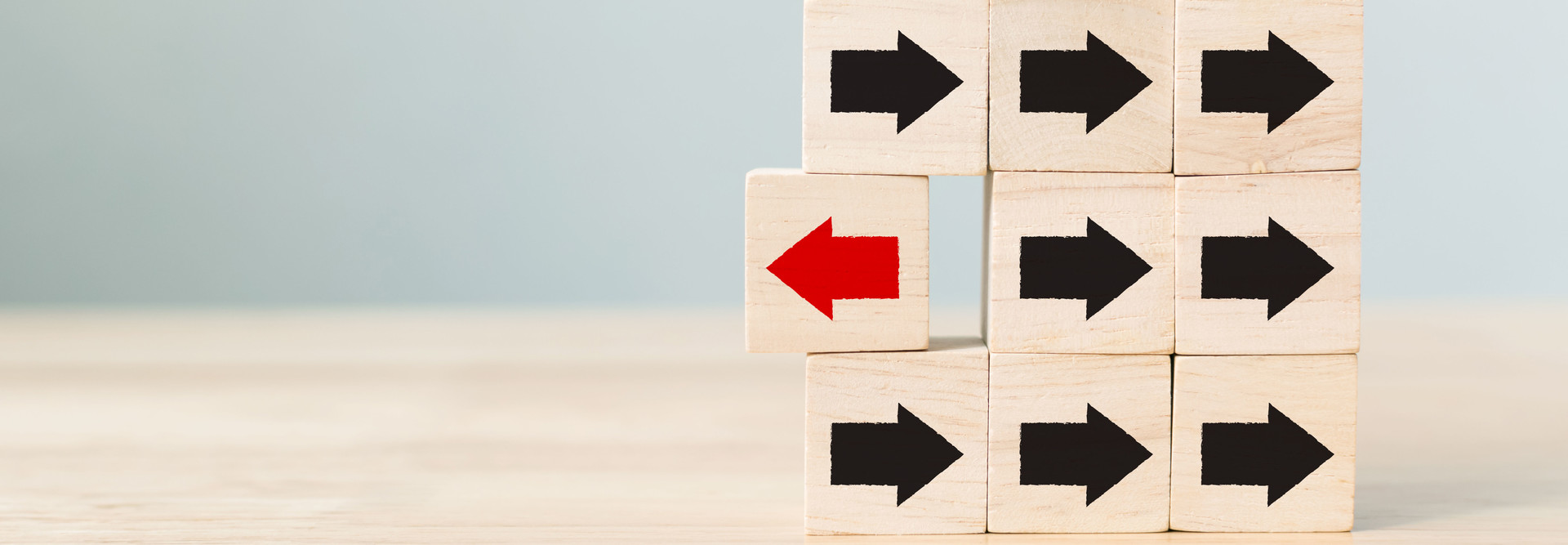 Wooden block with red arrow facing the opposite direction black arrows