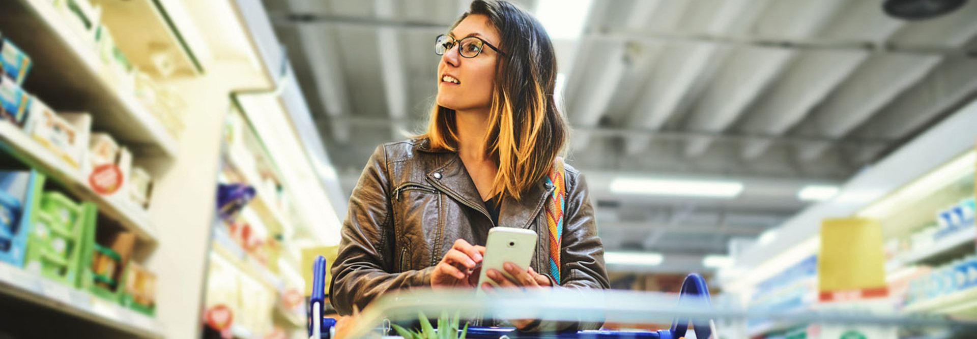 Shot of a young woman using a mobile phone in a grocery store