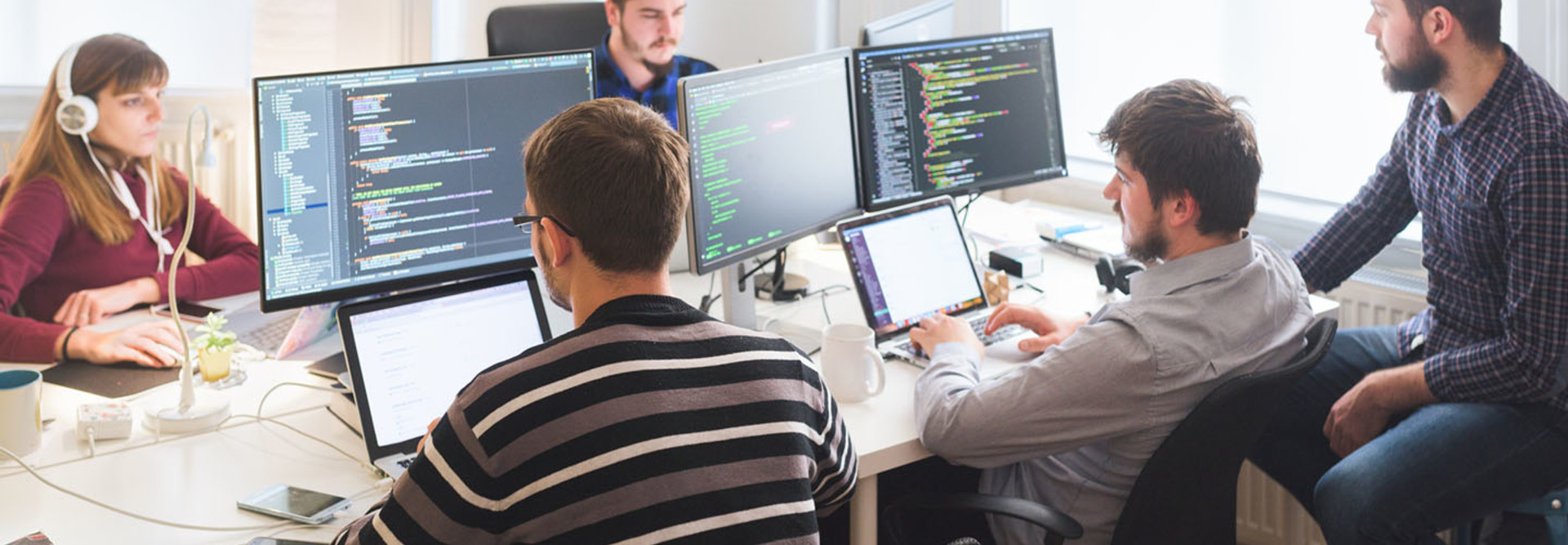  Group of software developers sitting at desktop computers being focused on their work