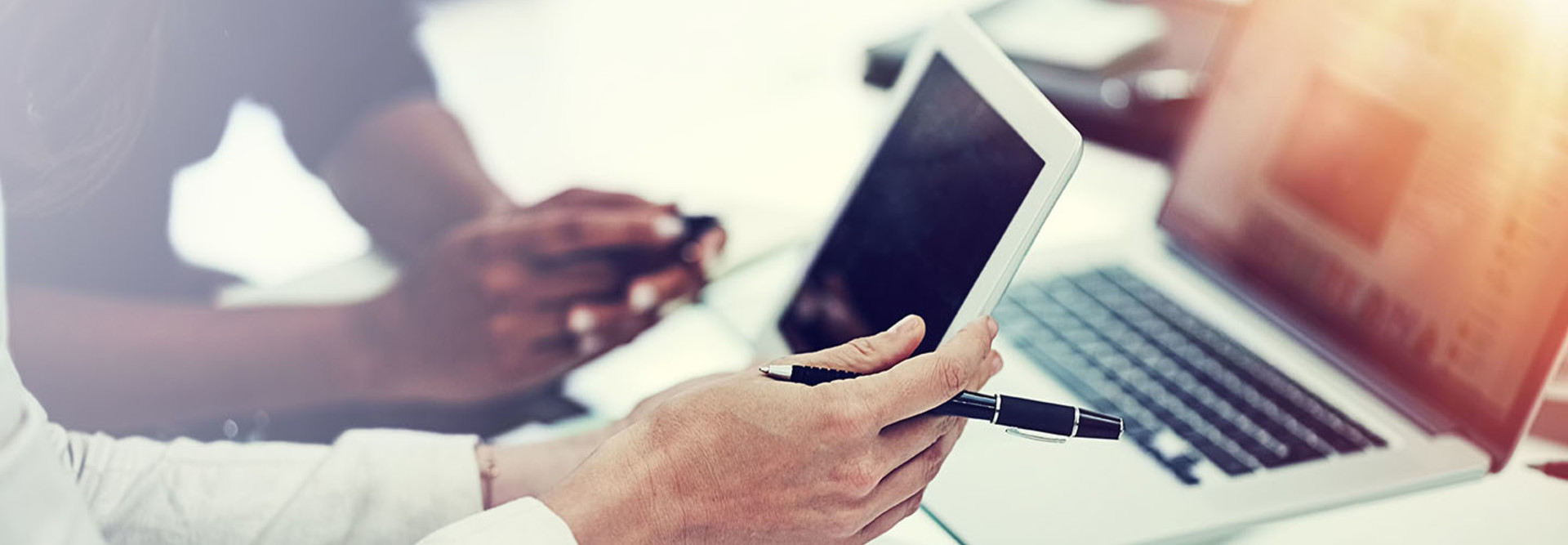 Woman holding tablet in front of a laptop