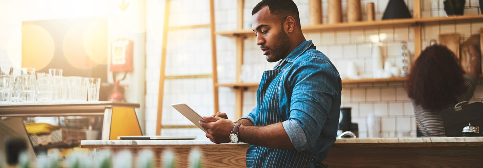 Cropped shot of a handsome young man working on a tablet in his coffee shop