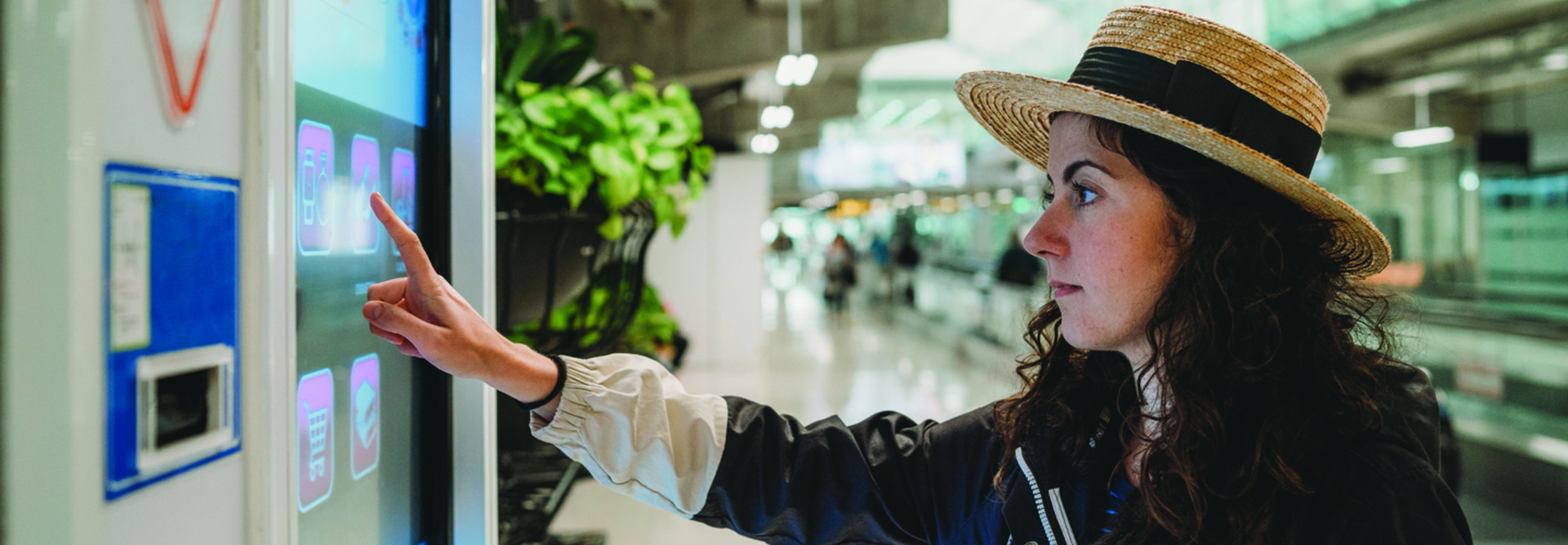 woman in hat pointing at a touchscreen sign