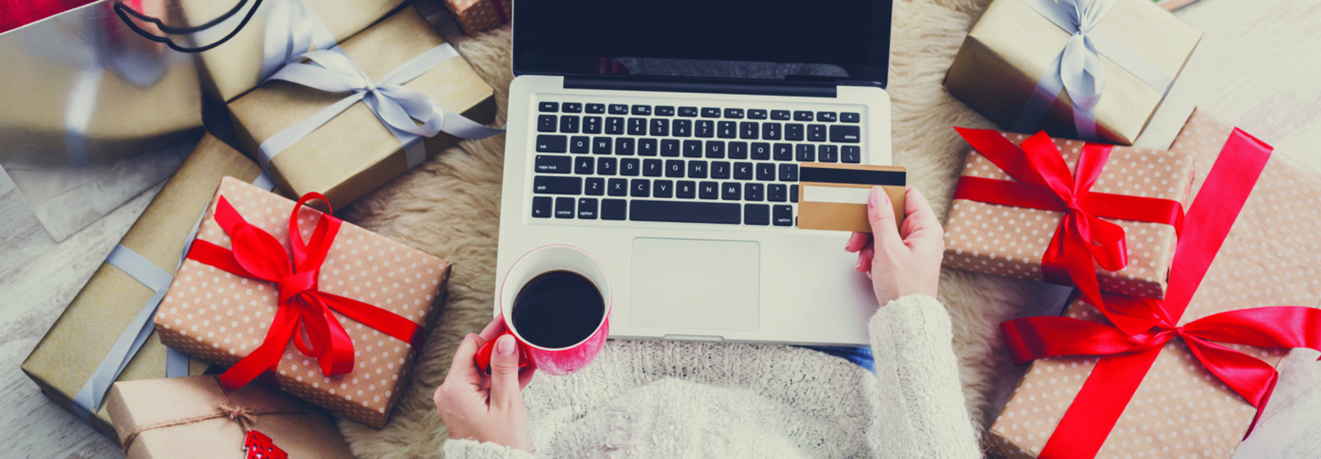 woman on laptop with credit card surrounded by gifts