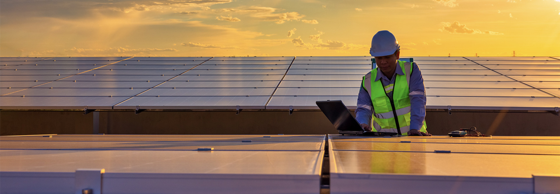 Engineer using laptop at solar panels