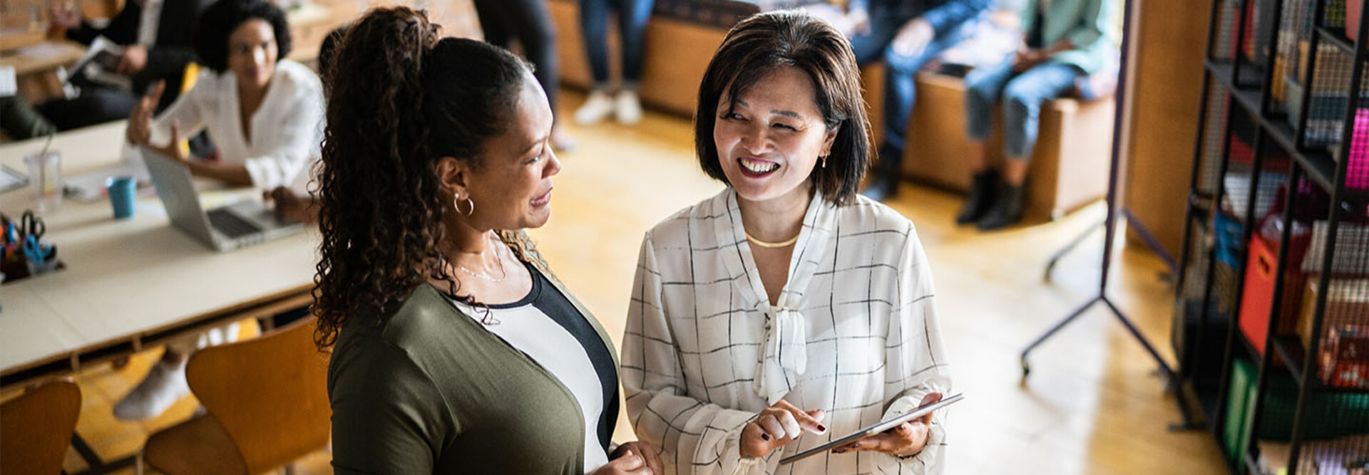 Two colleagues talking and using a digital tablet at work