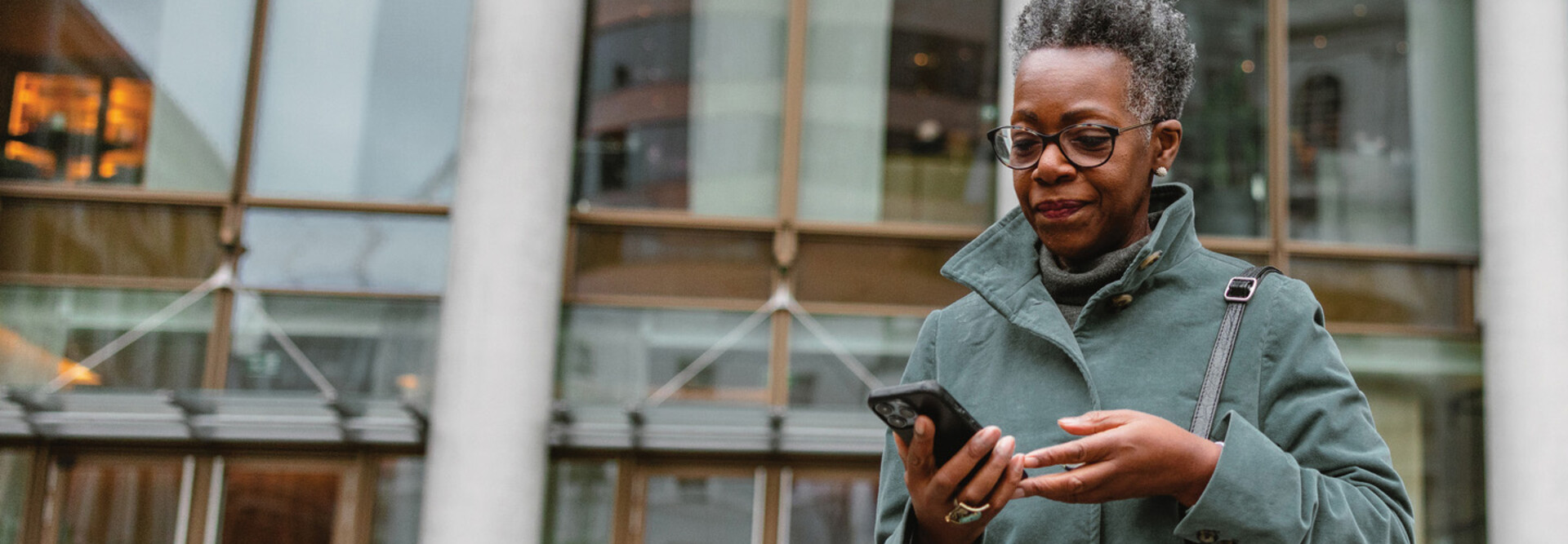 A woman on a smartphone in front of a sleek office building