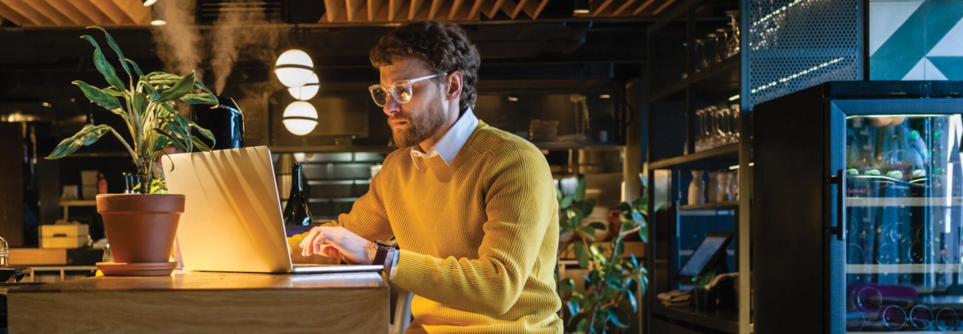 Businessman using laptop while sitting on seat at counter in cafe