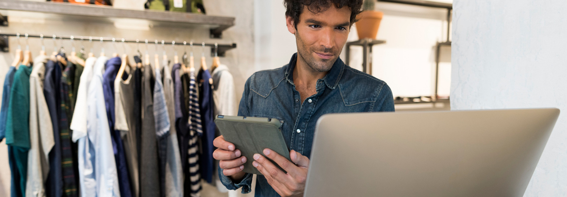 Male retail worker looking at data analytics on a monitor in a retail store 
