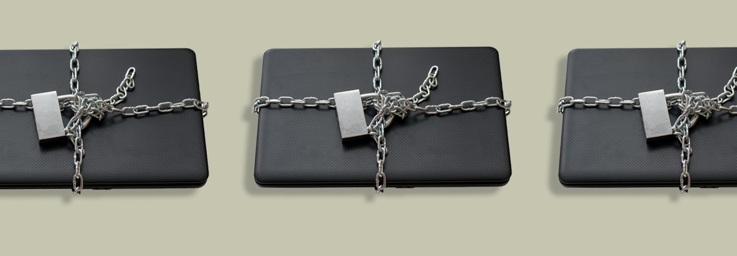 Closed laptop wrapped around with metal chain and locked with padlock