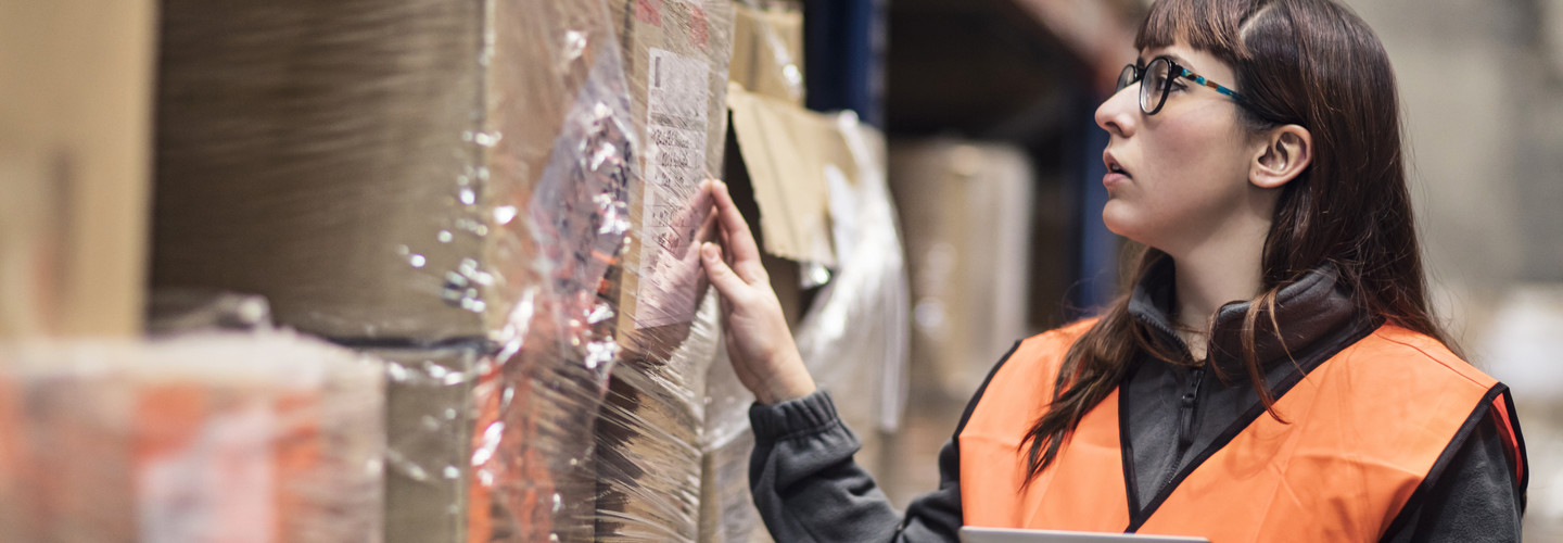 Woman doing inventory of boxes in a warehouse
