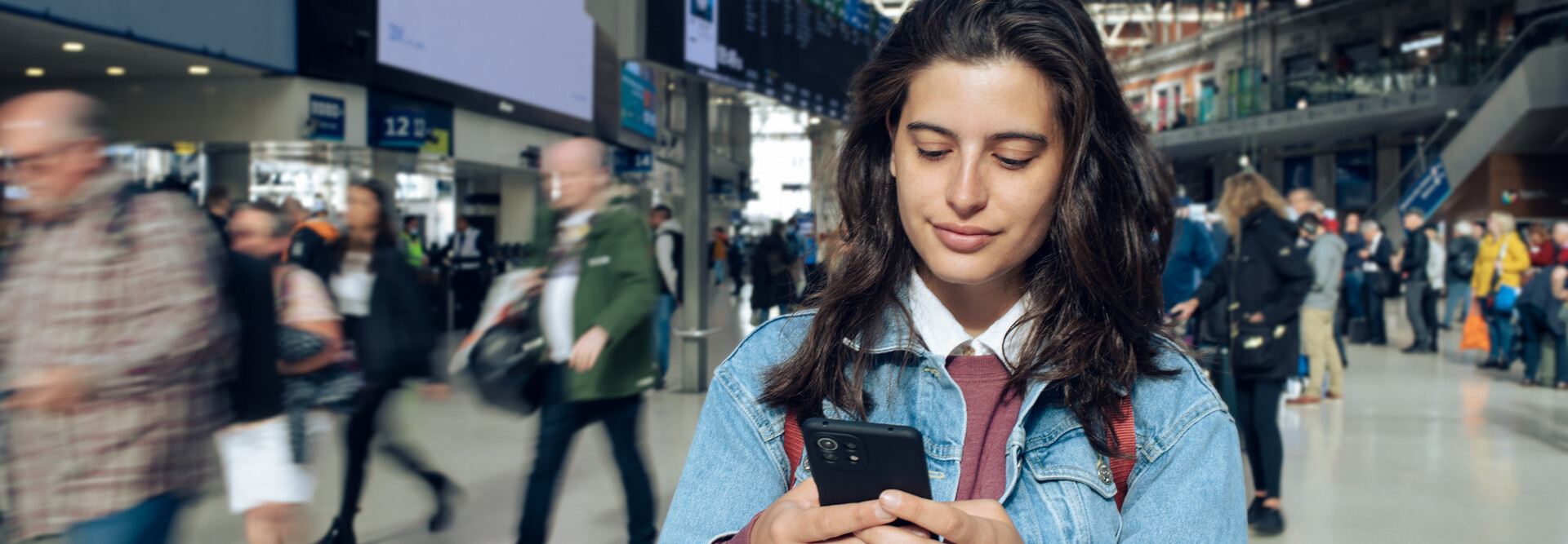 Woman looking at phone at a train station 
