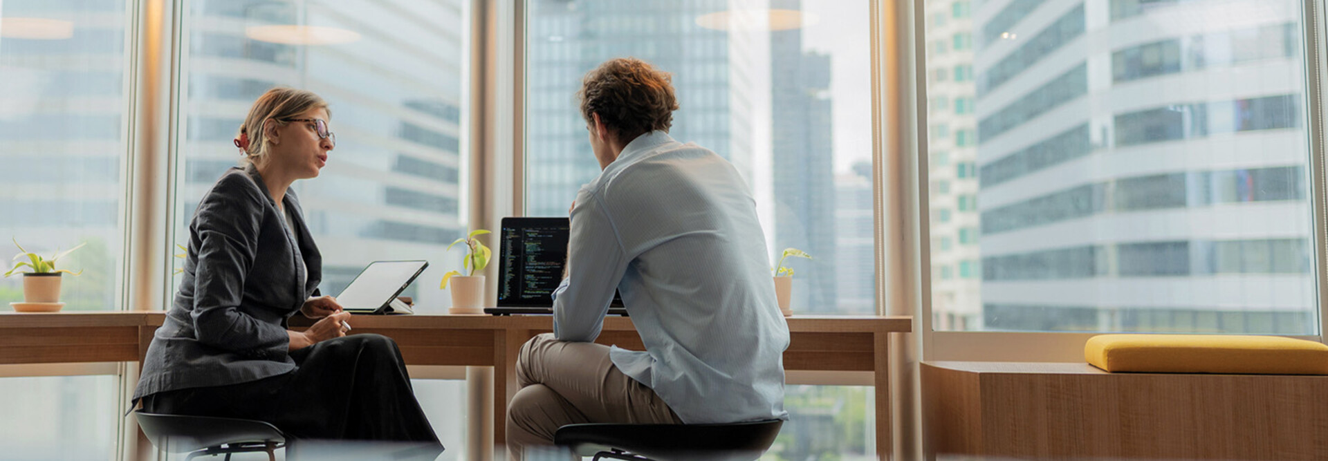 Adviser in modern office working on computer while speaking with clients