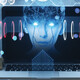 Hacker holding computer with floating face representing AI cyberattacks