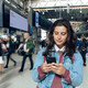Woman looking at phone at a train station 