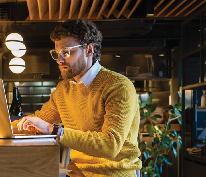 Businessman using laptop while sitting on seat at counter in cafe