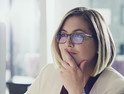 Woman CIO with glasses and dirty blonde hair sitting at her computer and thinking