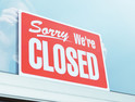A retailer hangs a "Closed" sign in a store window