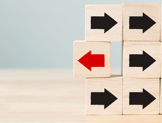 Wooden block with red arrow facing the opposite direction black arrows