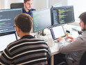  Group of software developers sitting at desktop computers being focused on their work