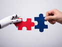 Robot and human hands putting puzzle pieces together
