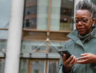 A woman on a smartphone in front of a sleek office building