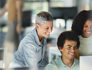 IT team smiles around computer