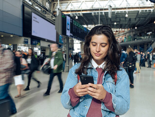 Woman looking at phone at a train station 