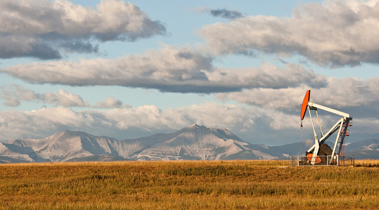 Remote oil well in Alberta, Canada, with mountains in the background 