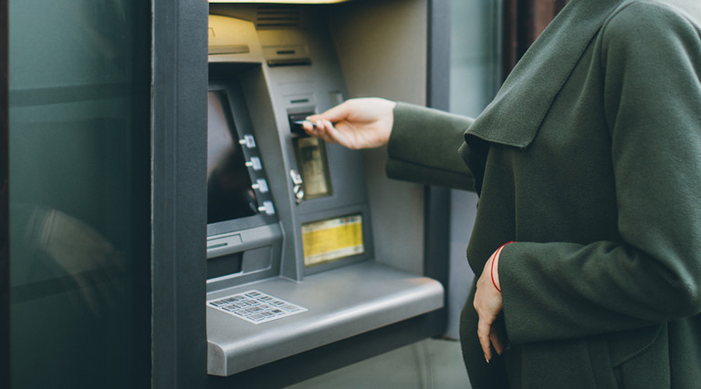 Woman in a green coat using an ATM 