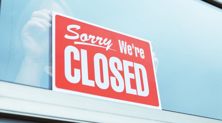 A retailer hangs a "Closed" sign in a store window