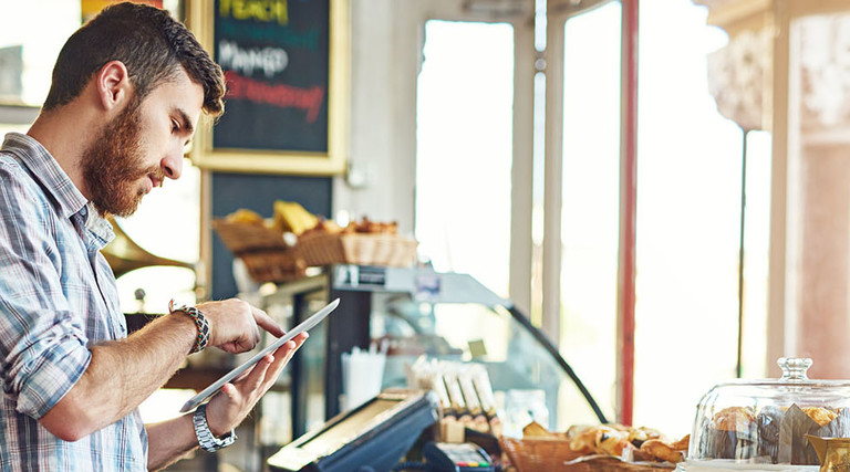 Shot of a young man using a digital tablet while working in a coffee shop