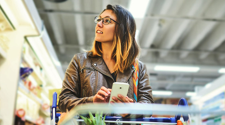 Shot of a young woman using a mobile phone in a grocery store