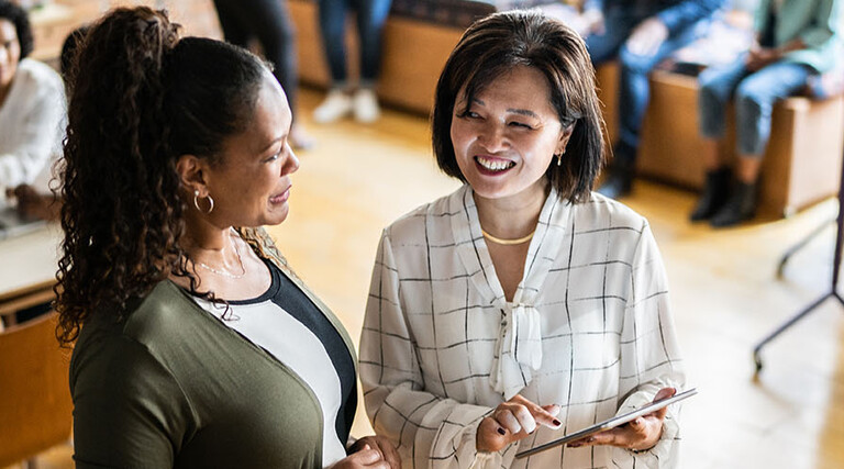 Two colleagues talking and using a digital tablet at work