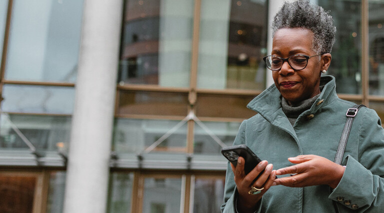 A woman on a smartphone in front of a sleek office building