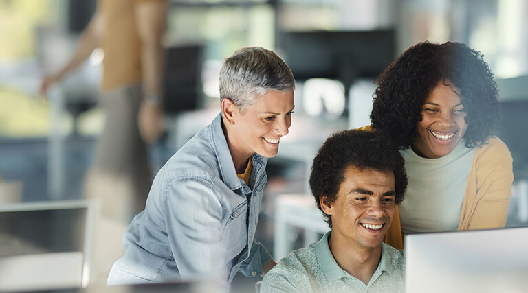 IT team smiles around computer
