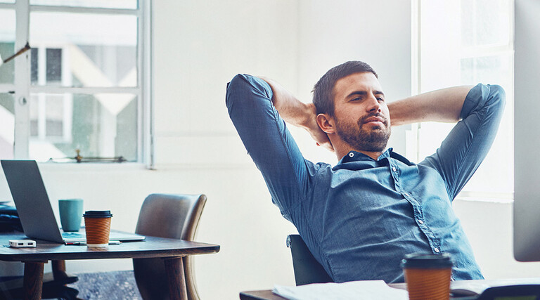 An employee leans back at his desk