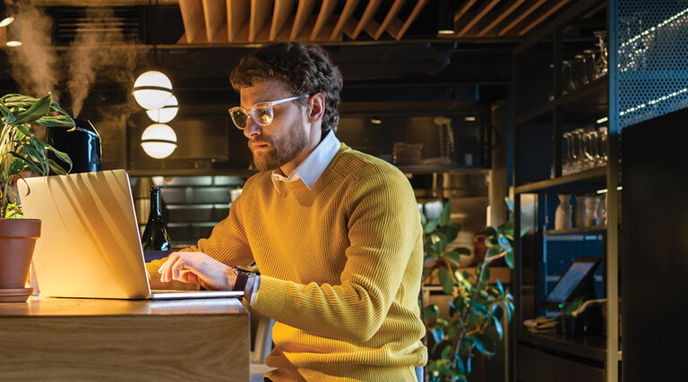 Businessman using laptop while sitting on seat at counter in cafe