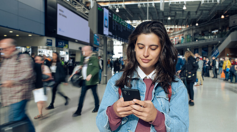 Woman looking at phone at a train station 