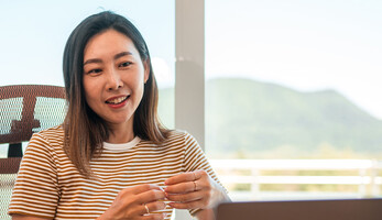A woman works from home using AI and a laptop