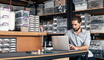 small business owner does inventory on his laptop