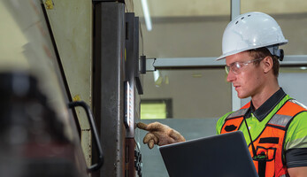 Worker checking a machine in a warehouse